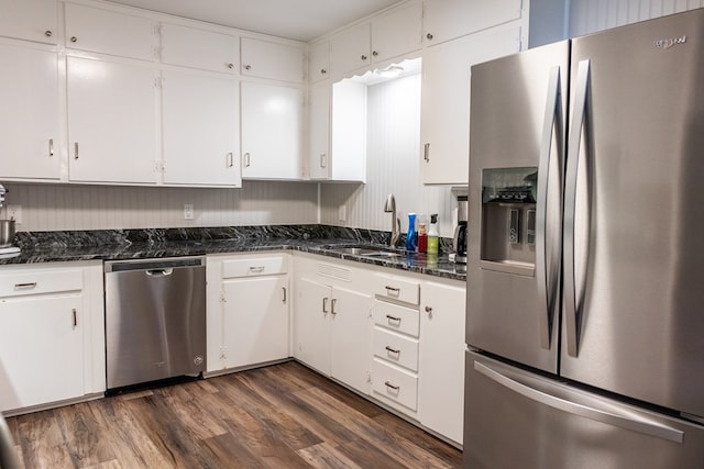 kitchen with dark stone countertops, stainless steel appliances, dark hardwood / wood-style floors, and white cabinets