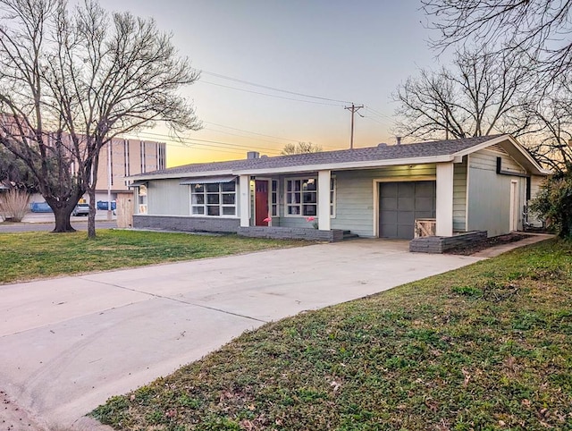 single story home featuring a garage and a lawn