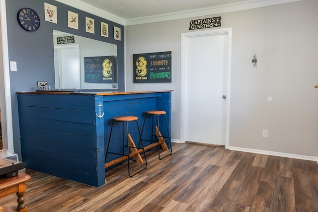 bar featuring dark wood-type flooring, ornamental molding, and a textured ceiling