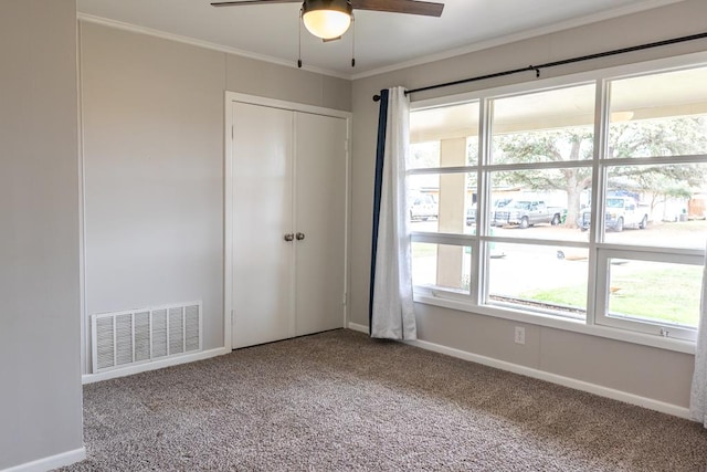 unfurnished bedroom with visible vents, multiple windows, carpet floors, and ornamental molding