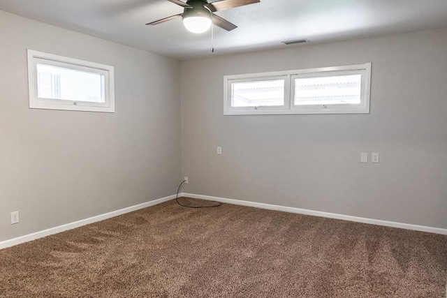 carpeted empty room with visible vents, baseboards, and a ceiling fan