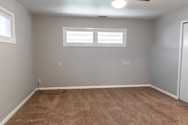 carpeted spare room featuring visible vents, baseboards, and ceiling fan