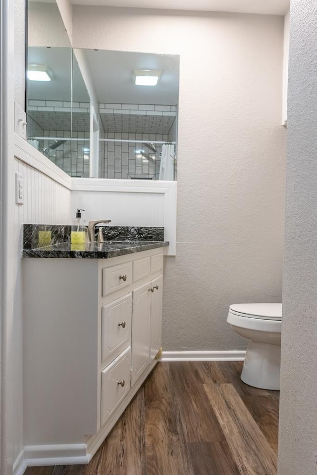 full bath featuring vanity, wood finished floors, baseboards, a shower, and toilet