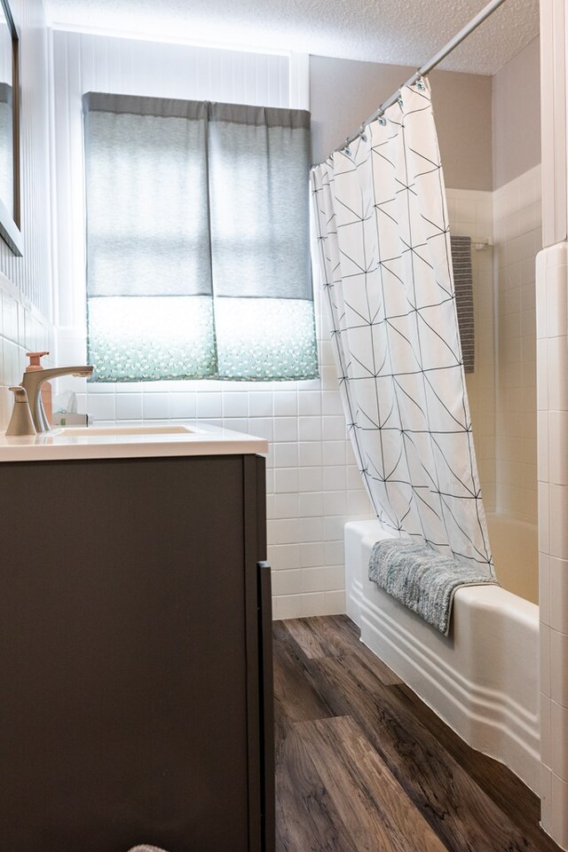 bathroom featuring shower / bath combination with curtain, plenty of natural light, wood-type flooring, and a textured ceiling