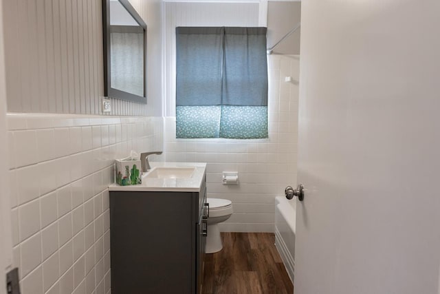 full bathroom with toilet, shower / tub combination, wood finished floors, tile walls, and vanity