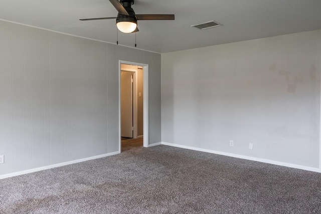 empty room featuring visible vents, baseboards, ceiling fan, and dark carpet