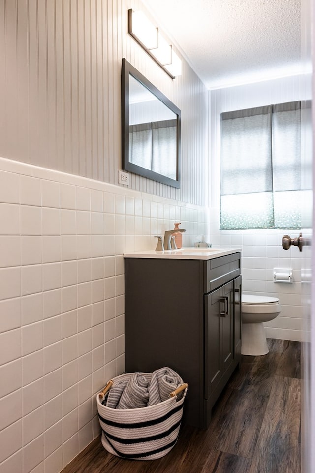 bathroom with hardwood / wood-style flooring, vanity, tile walls, and a textured ceiling