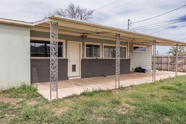 rear view of house featuring brick siding and fence