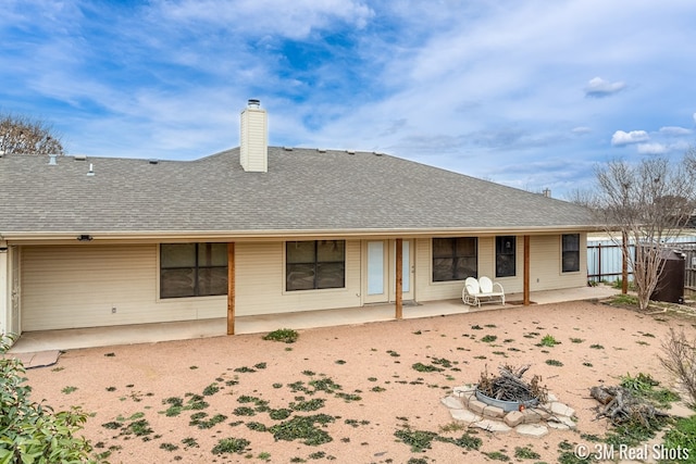 back of house with a fire pit, a shingled roof, fence, a chimney, and a patio area