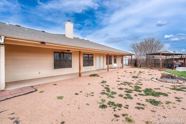 back of house with a patio area, a shingled roof, a chimney, and fence