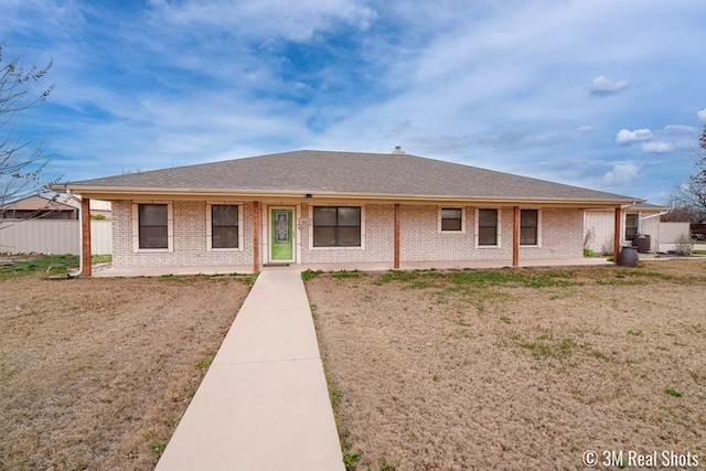 rear view of property with roof with shingles, fence, a lawn, and brick siding