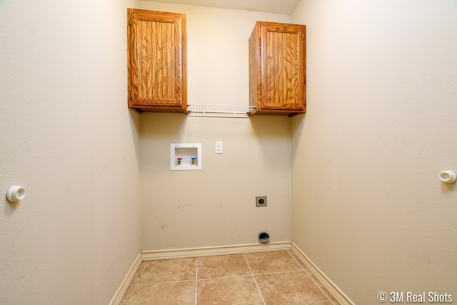 washroom with hookup for a washing machine, cabinet space, hookup for an electric dryer, light tile patterned flooring, and baseboards