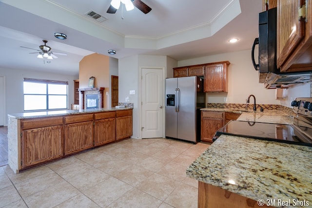 kitchen featuring a peninsula, visible vents, stainless steel fridge with ice dispenser, brown cabinets, and a raised ceiling