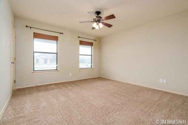 carpeted spare room featuring ceiling fan and baseboards