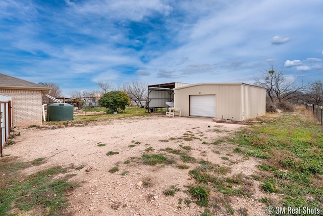 view of yard featuring a garage, dirt driveway, and an outbuilding