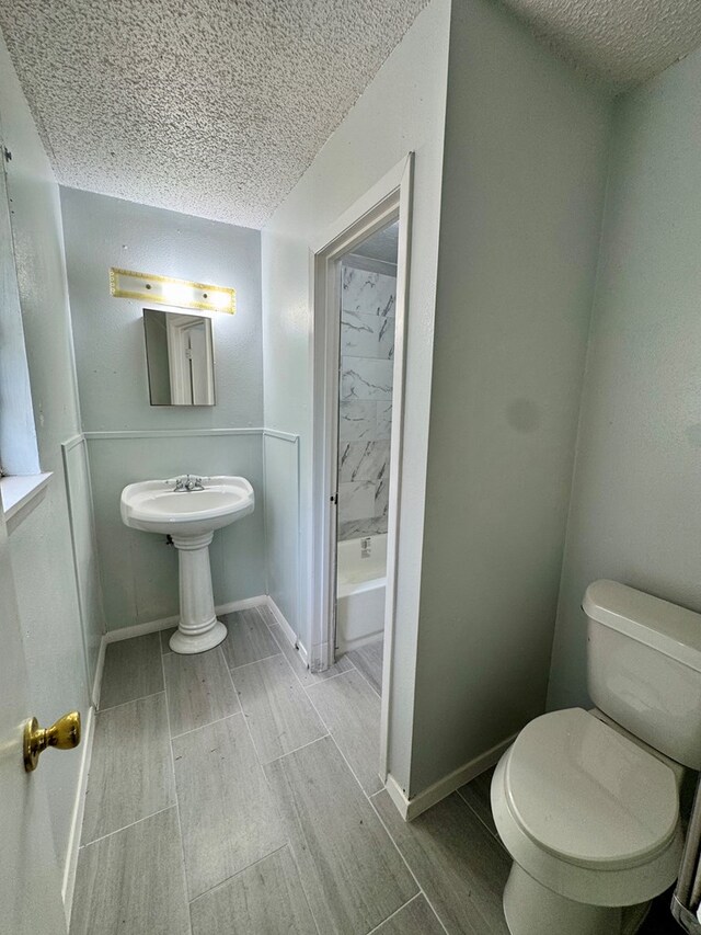 1025 Linda Lee Dr, San Angelo, TX 76905 - full bath with toilet, wood finish floors, a textured ceiling, and baseboards