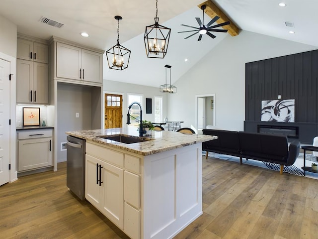 kitchen with sink, light stone counters, a center island with sink, decorative light fixtures, and stainless steel dishwasher