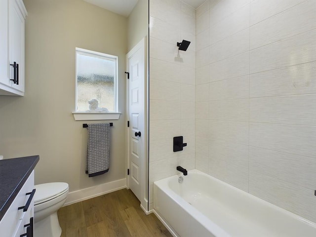 full bathroom featuring hardwood / wood-style flooring, vanity, tiled shower / bath combo, and toilet