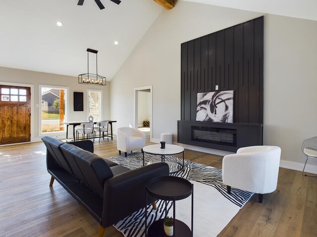 living room featuring ceiling fan, hardwood / wood-style floors, beam ceiling, high vaulted ceiling, and a fireplace