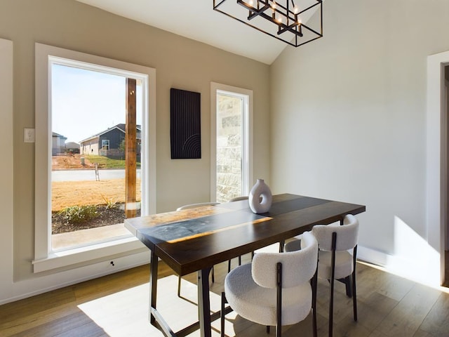 dining area featuring wood-type flooring, a chandelier, and vaulted ceiling