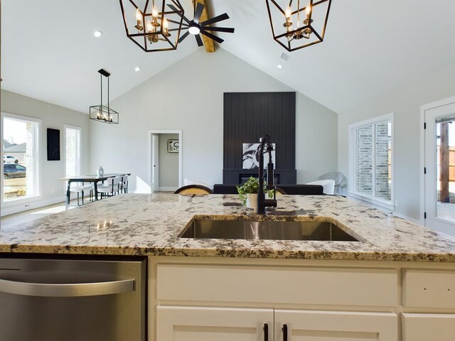 kitchen with sink, beam ceiling, light stone countertops, stainless steel dishwasher, and a chandelier