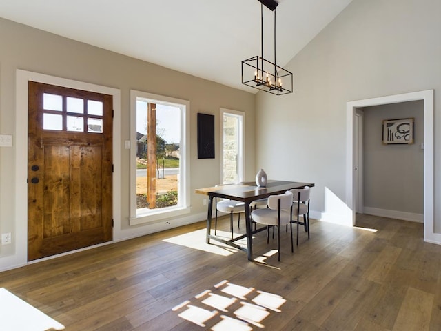 dining space featuring high vaulted ceiling, an inviting chandelier, and dark hardwood / wood-style flooring