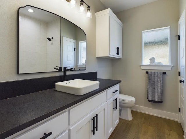 bathroom with hardwood / wood-style flooring, vanity, toilet, and walk in shower