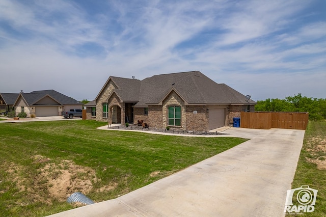 french country home featuring brick siding, fence, driveway, stone siding, and a front lawn
