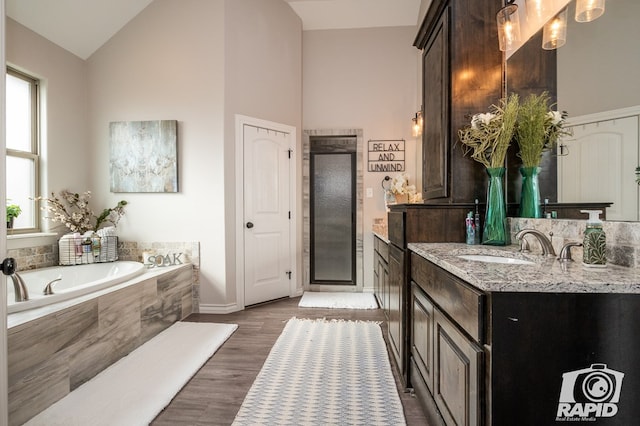 full bathroom featuring vanity, high vaulted ceiling, a stall shower, a garden tub, and wood finished floors