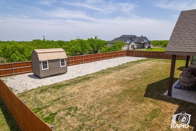 view of yard featuring an outdoor structure, a storage unit, and a fenced backyard