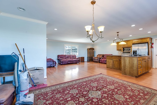 kitchen with hanging light fixtures, ornamental molding, stainless steel appliances, an inviting chandelier, and light hardwood / wood-style flooring