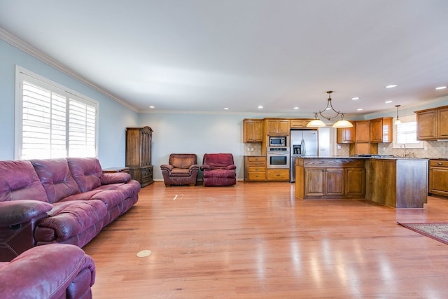 living room with ornamental molding, sink, and light hardwood / wood-style flooring