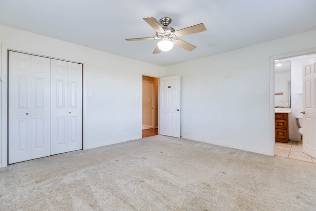 unfurnished bedroom featuring ceiling fan, light carpet, ensuite bath, and a closet