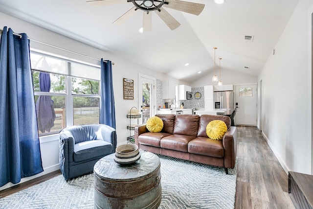 living room with ceiling fan, light hardwood / wood-style floors, and vaulted ceiling