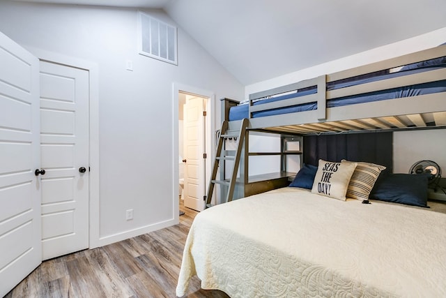 bedroom featuring hardwood / wood-style floors, vaulted ceiling, and ensuite bathroom