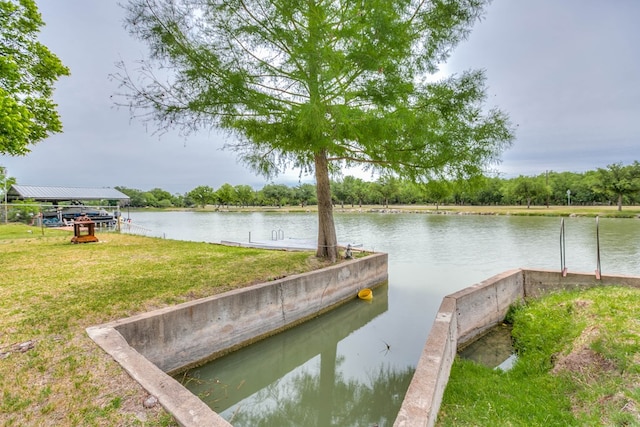 view of dock featuring a lawn and a water view