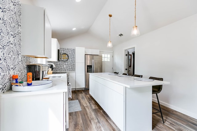 kitchen with decorative light fixtures, white cabinets, a kitchen bar, decorative backsplash, and stainless steel fridge with ice dispenser