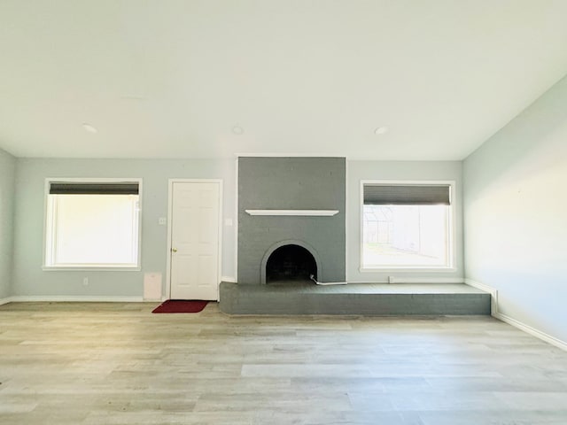 unfurnished living room featuring light hardwood / wood-style flooring and a large fireplace