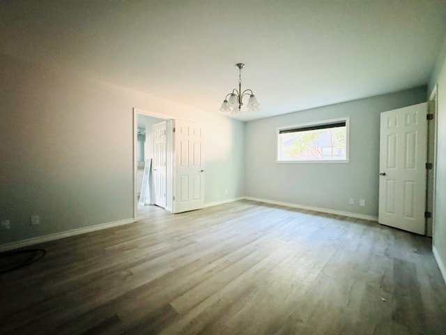 unfurnished room featuring wood-type flooring and a chandelier