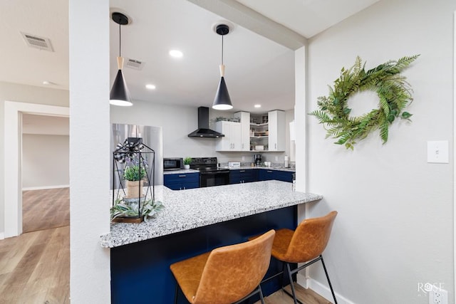 kitchen featuring white cabinetry, black electric range oven, a kitchen breakfast bar, kitchen peninsula, and wall chimney exhaust hood