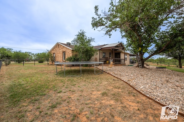 rear view of house with a yard, a deck, and a trampoline