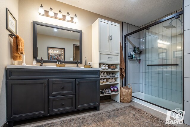 bathroom featuring vanity, hardwood / wood-style flooring, a shower with door, and a textured ceiling