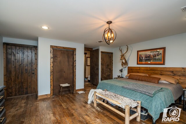 bedroom with multiple closets, dark wood-type flooring, and a chandelier