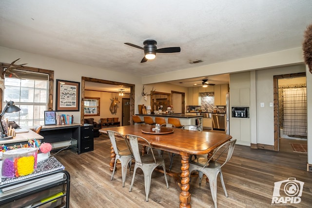 dining room with ceiling fan, dark wood-type flooring, and a textured ceiling