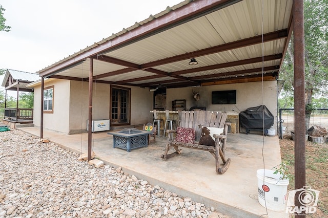 view of patio featuring area for grilling, a bar, and a fire pit