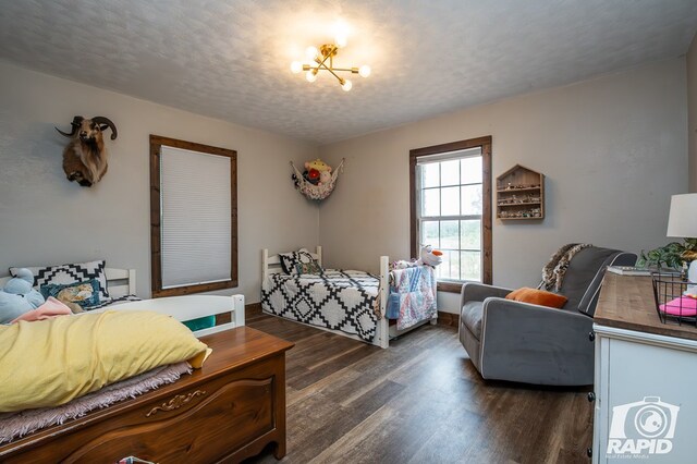 bedroom featuring a chandelier, dark hardwood / wood-style floors, and a textured ceiling