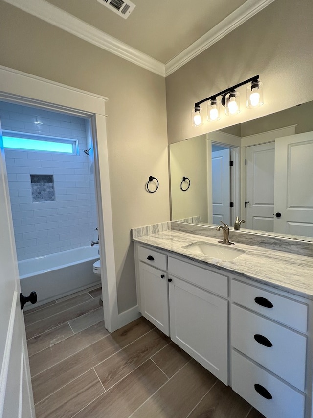 full bathroom featuring vanity, tiled shower / bath combo, ornamental molding, and toilet