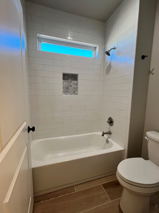 bathroom featuring a healthy amount of sunlight, tiled shower / bath combo, and toilet