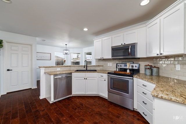 kitchen with decorative light fixtures, white cabinetry, sink, backsplash, and stainless steel appliances