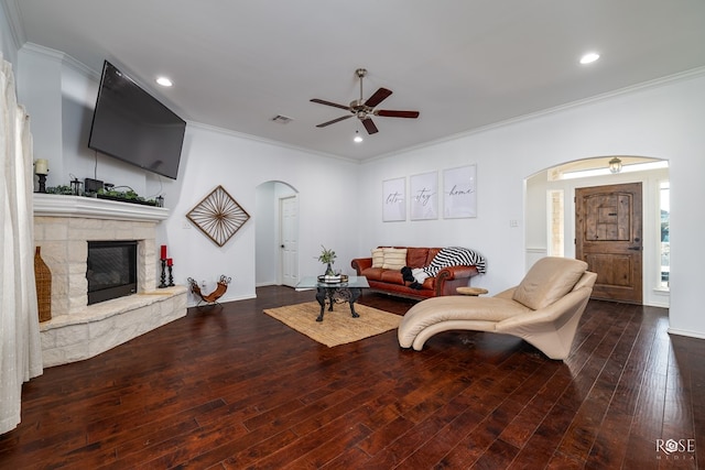 living room featuring crown molding, hardwood / wood-style floors, ceiling fan, and a fireplace